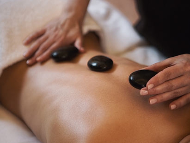 woman getting a massage and hot stones at The Ritz-Carlton Residences Sarasota Bay Spa