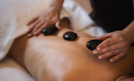 woman getting a massage and hot stones at The Ritz-Carlton Residences Sarasota Bay Spa