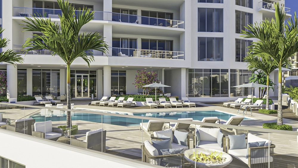 Modern luxury pool deck with lounge seating, palm trees, and waterfront views at a residential tower.