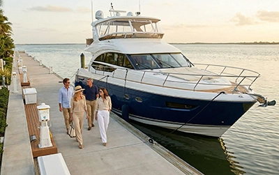 People walking along a marina beside a luxury yacht on Sarasota Bay.
