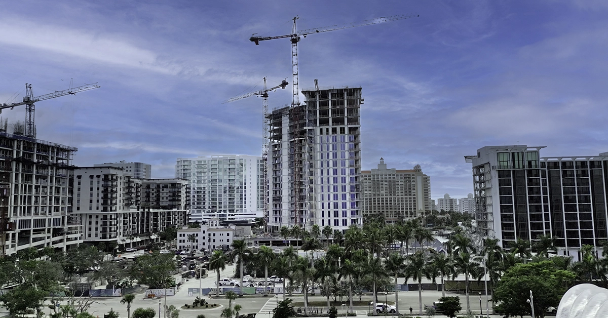 High-rise tower under construction with cranes along Sarasota Bay.