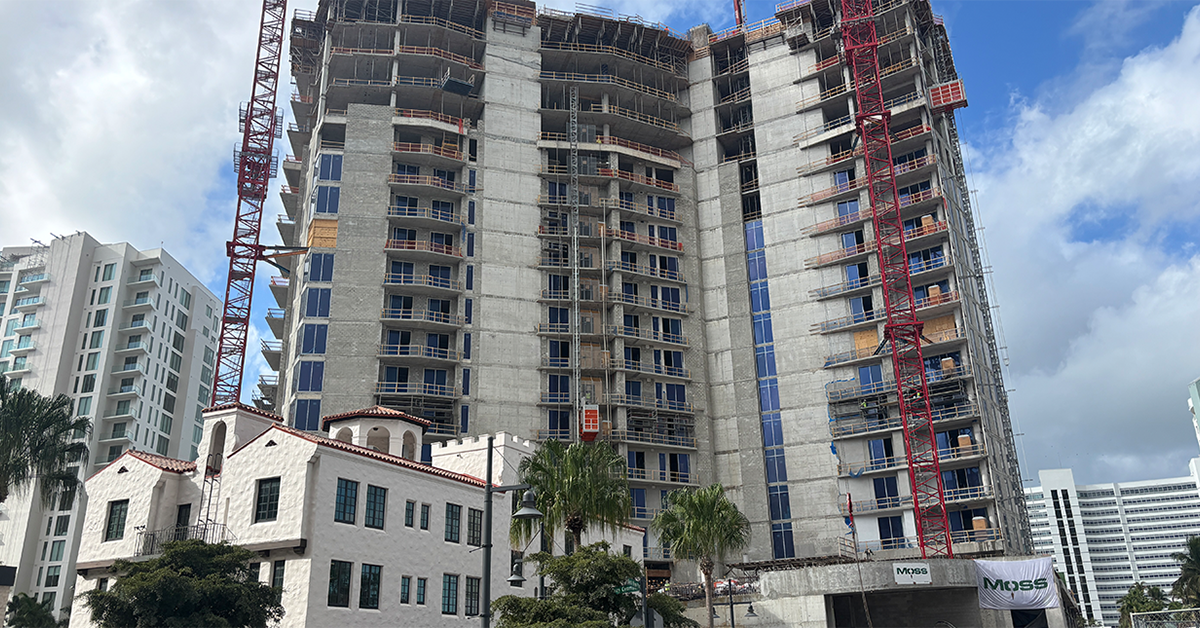 High-rise residential building under construction with cranes and scaffolding.