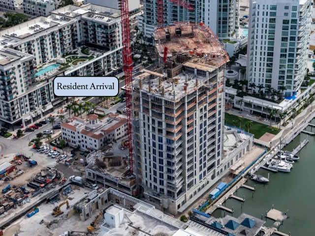 Upper floors of waterfront tower under construction next to marina docks.