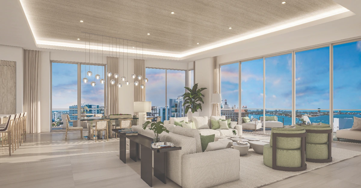 Open-concept great room with kitchen, dining area, lounge seating, and floor-to-ceiling windows facing the water.