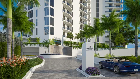 Entrance driveway to The Ritz-Carlton Residences with palm trees, tropical flowers, a monument sign, and a blue convertible car.